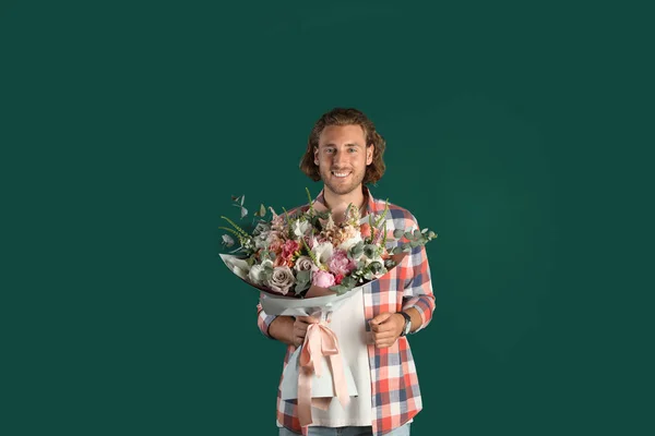 Jeune homme beau avec beau bouquet de fleurs sur fond vert — Photo