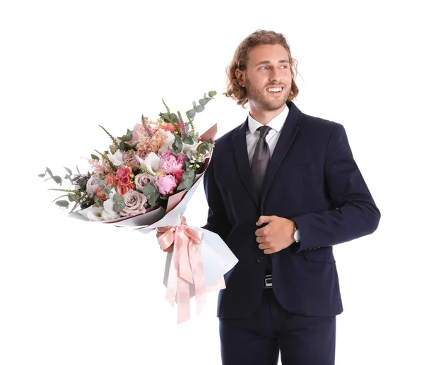 Jovem homem bonito em terno elegante com lindo buquê de flores no fundo branco — Fotografia de Stock