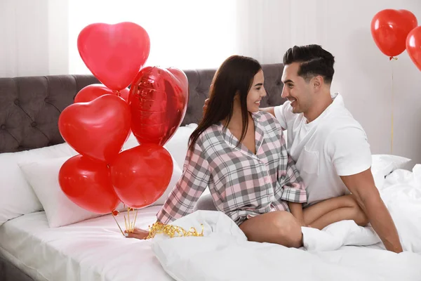 Piękna para z balonem w kształcie serca w sypialni — Zdjęcie stockowe