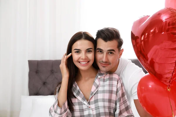 Όμορφο ζευγάρι με τα μπαλόνια σε σχήμα καρδιάς στο υπνοδωμάτιο — Φωτογραφία Αρχείου
