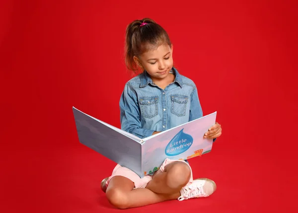 赤い背景に本を読んでかわいい女の子 — ストック写真