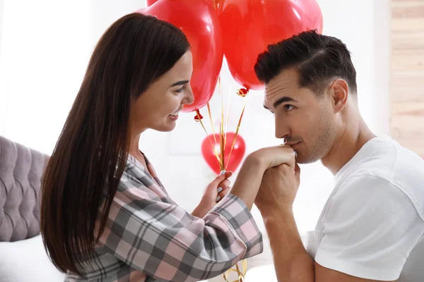 Hermosa pareja con globos en forma de corazón en el dormitorio — Foto de Stock