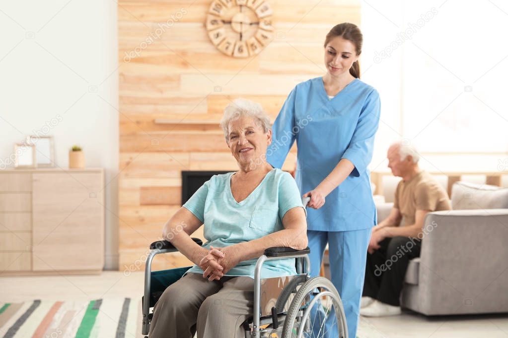 Nurse assisting elderly woman in wheelchair at retirement home. Space for text