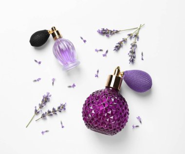 Beyaz arka planda doğal parfüm ve lavanta çiçekleri şişeleri, üst görünümü. Kozmetik ürünler
