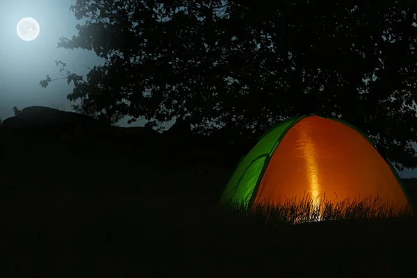 Modernt tält upplyst inifrån i vildmarken på natten, plats för text. Övernattning Camping — Stockfoto