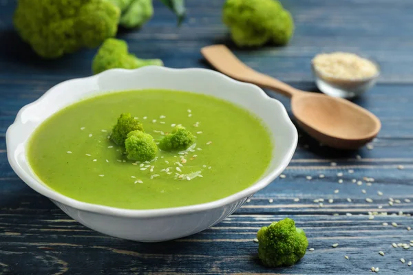 Ciotola di broccoli crema zuppa con semi di sesamo servita su tavolo di legno blu — Foto Stock