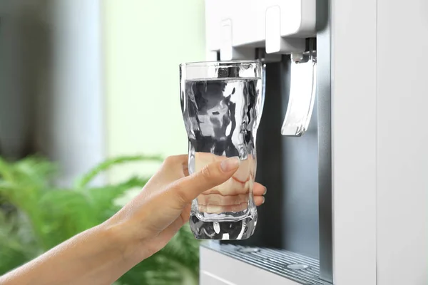 Woman filling glass from water cooler indoors, closeup. Refreshing drink — Stock Photo, Image