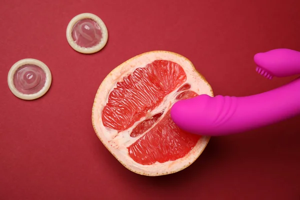 Hälfte Grapefruit, lila Vibrator und Kondome auf rotem Hintergrund, flach liegend. Sexualkonzept — Stockfoto