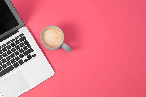 Nowoczesny laptop i filiżanka kawy na różowym tle, widok z góry. Miejsce na tekst — Zdjęcie stockowe