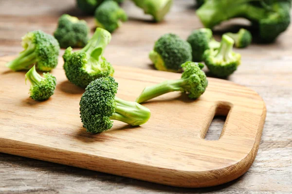 Papan kayu dengan brokoli segar di atas meja, closeup — Stok Foto
