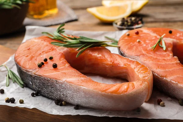 Fresh salmon steaks with spices and rosemary on table, closeup view — Stock Photo, Image
