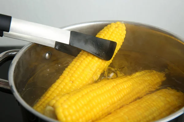 Tomando espiga de milho fresco de panela com água quente no fogão — Fotografia de Stock
