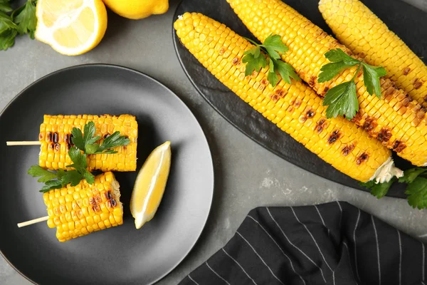 Composición plana de mazorcas de maíz a la parrilla sobre mesa gris —  Fotos de Stock