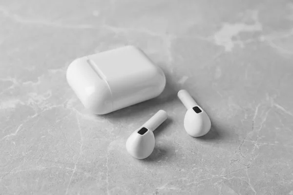 Fones de ouvido sem fio e estojo de carregamento na mesa de mármore cinza claro — Fotografia de Stock