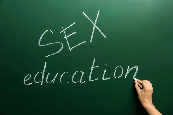 Mujer escribiendo frase "SEXO EDUCACIÓN" en pizarra verde — Foto de Stock