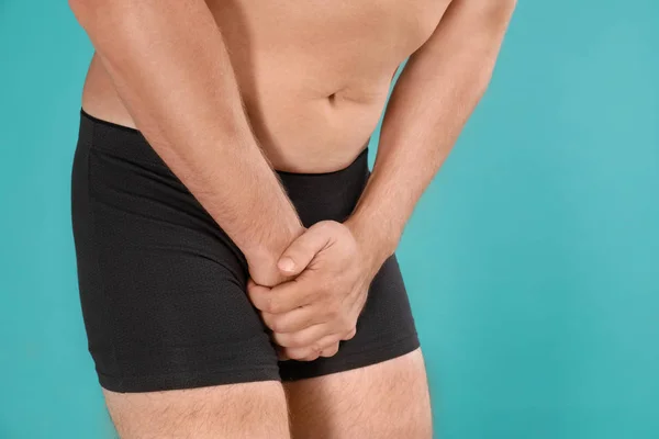 Man die lijdt aan pijn op Turquoise achtergrond, close-up. Urologie problemen — Stockfoto