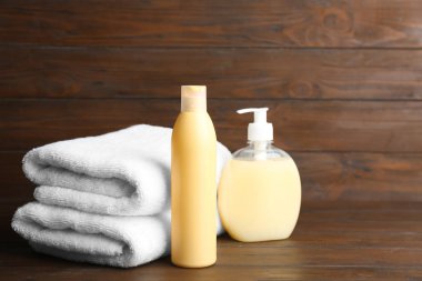 Ahşap masa üzerinde katlanmış yumuşak havlu ve banyo malzemeleri