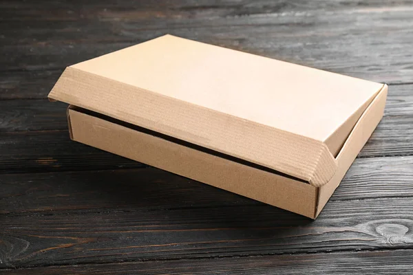 Open cardboard box on black wooden table — Stock Photo, Image