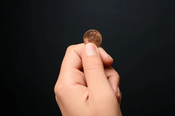 Mujer joven sosteniendo moneda sobre fondo negro, vista de cerca — Foto de Stock