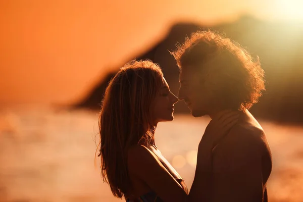 Bikinili genç kadın ve gün batımında sahilde erkek arkadaşı. Güzel çift — Stok fotoğraf