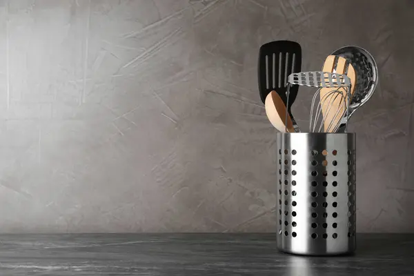 Soporte con utensilios de cocina sobre mesa gris sobre fondo de piedra gris. Espacio para texto — Foto de Stock