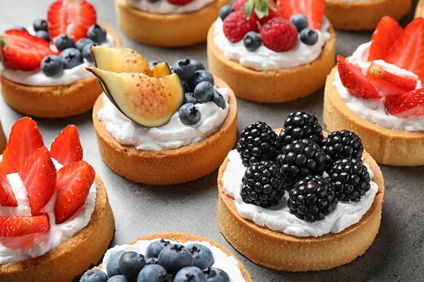 Many different berry tarts on table. Delicious pastries