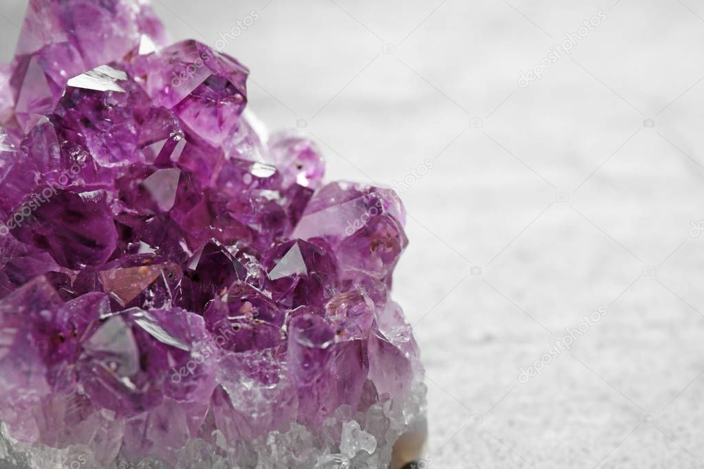 Beautiful purple amethyst gemstone on grey table, closeup view. Space for text