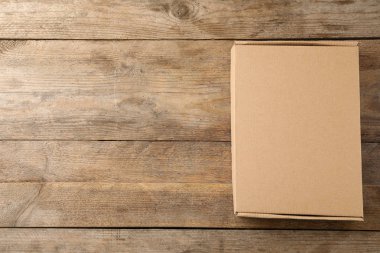 Ahşap arka plan üzerinde kapalı karton kutu, üst görünüm. Metin için alan