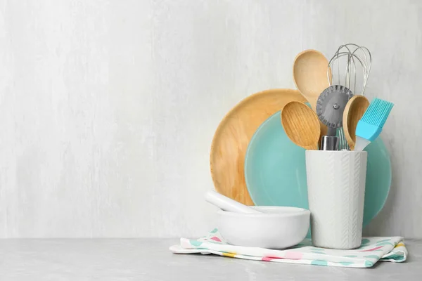 Verschiedene Küchenutensilien auf grauem Tisch vor hellem Hintergrund. Raum für Text — Stockfoto