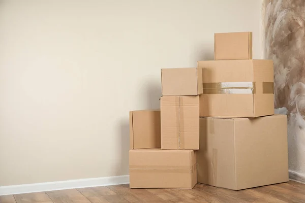 Pilha de caixas de papelão perto de parede leve dentro de casa. Espaço para texto — Fotografia de Stock