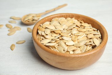 Beyaz ahşap masa üzerinde ham kabak çekirdeği Kase