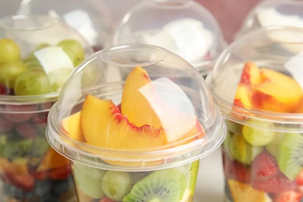 Salade de fruits frais savoureux dans des tasses en plastique, gros plan — Photo