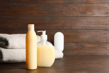 Ahşap masa üzerinde katlanmış yumuşak havlu ve banyo malzemeleri