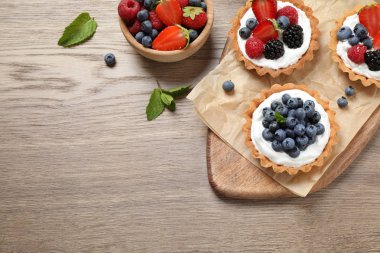 Ahşap masa üzerinde farklı berry tarts, düz metin için alan ile yatıyordu. Lezzetli hamur işleri