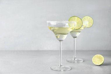 Gri arka plan karşı açık masada limon dilim li limon damla martini kokteyl bardak. Metin için alan