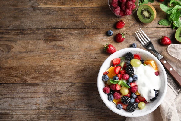 Frischer, schmackhafter Obstsalat mit Joghurt auf Holztisch, flach gelegt. Raum für Text — Stockfoto