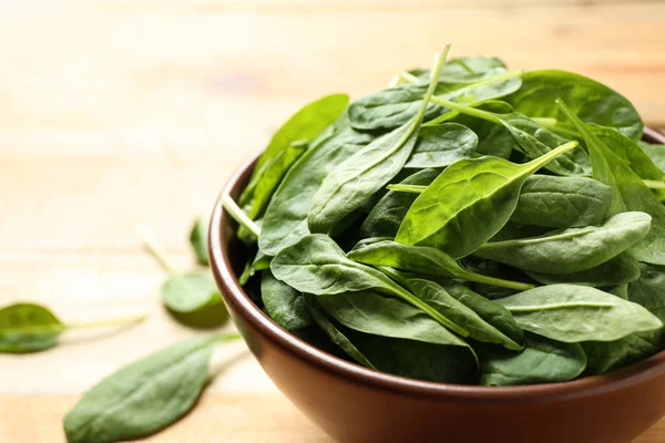 Bowl of fresh green healthy spinach on wooden table, closeup — Stock Photo, Image