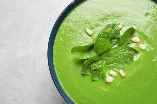 Tigela de sopa verde saudável com espinafre fresco na mesa cinza, vista superior — Fotografia de Stock