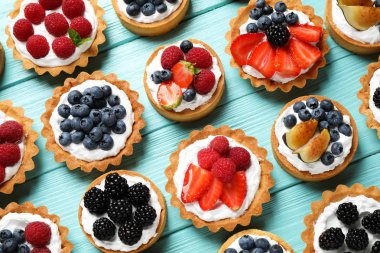 Mavi ahşap masa üzerinde birçok farklı berry tart, düz yatıyordu. Lezzetli hamur işleri