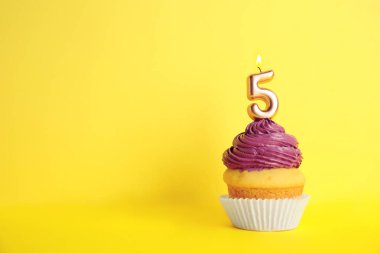 Sarı arka plan üzerinde beş numaralı mum ile Doğum günü cupcake, metin için alan