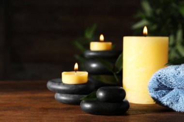 Ahşap masa üzerinde mumlar ve spa taşları ile kompozisyon. Metin için alan