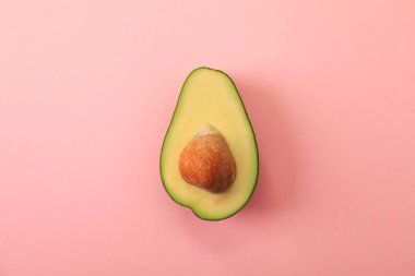 Pembe arka planda lezzetli avokado yarısı, üst görünümü