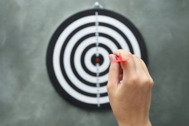 Kadın gri arka plan üzerinde dart tahtası kırmızı ok atma, closeup