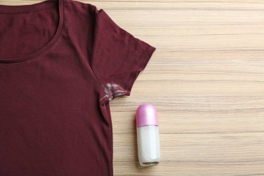Ahşap arka planda leke ve deodorant lı tişört, üst görünüm. Metin için alan