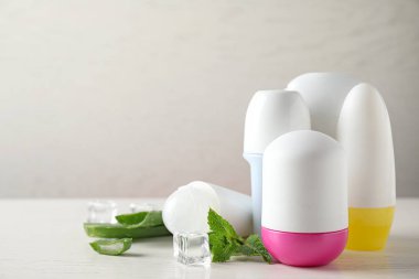 Roll-on deodorantlar, aloe ve beyaz ahşap masa üzerinde nane ile buz, metin için alan