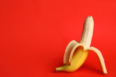 Fresh banana on red background, space for text. Sex concept clipart