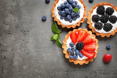 Gri masada farklı meyveleri ile Tarts, metin için alan ile üst görünüm. Lezzetli hamur işleri