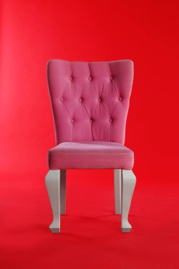 Kırmızı arka plan üzerinde şık pembe sandalye. İç tasarım unsuru