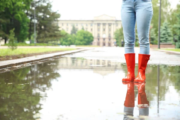 Femme avec des bottes en caoutchouc dans la flaque, gros plan. Météo pluvieuse — Photo