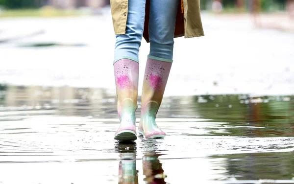 水たまりの中にゴムブーツを持つ女性、クローズアップ。雨天 — ストック写真